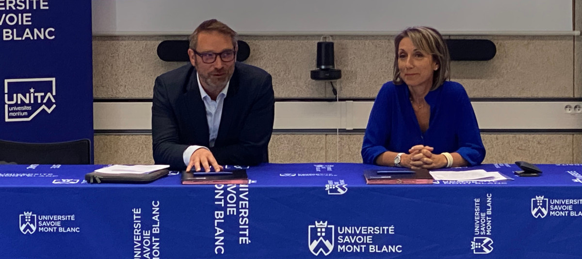 Deux personnes assises qui s'apprêtent à signer un document officiel.