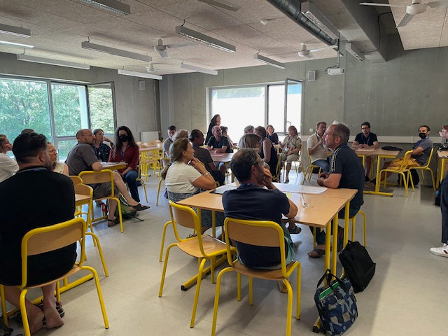 Enseignants regroupés en groupe de travail composé d'ilots de tables et de chaises