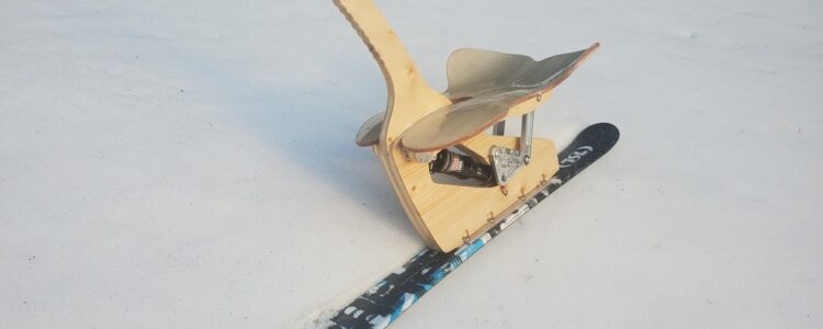 Photo of the wooden sled designed by GMP2 students. It is shown in profile, with a wooden seat and a ski for gliding.