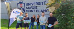 Les six doctorants dont la thèse est vulgarisée en BD se tiennent debout devant le logo de l'Université Savoie Mont Blanc. Ils tiennent chacun une BD à la main.