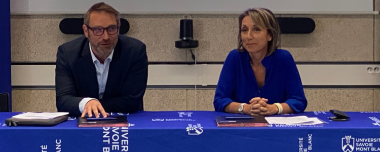 Deux personnes sont assises à une table aux couleurs de l'USMB, pour signer un document.